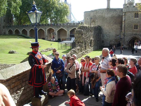 Beefeater guard talking to tourists in the courtyard at the Tower of London