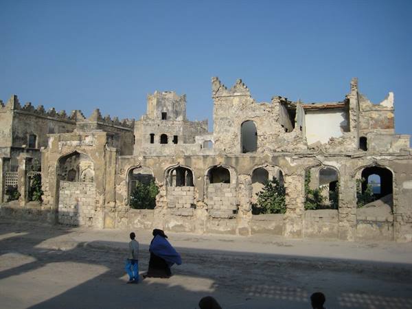 Woman and child walk past a ruined arched building in Mogadishu