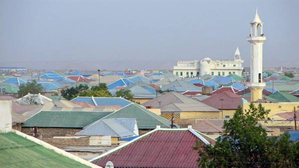 Corrugated metal rooftops and white minaret rise above the hazy town