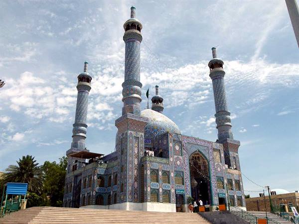 Shrine with blue tiled minarets and dome, stairs with few visitors