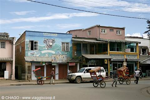 Hand-pulled rickshaws passing colorful buildings on a dusty street
