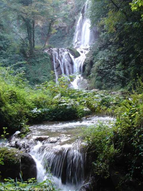Villanova waterfall flowing over mossy rocks amid lush greenery