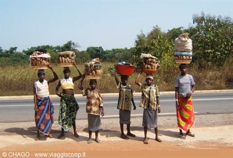 African women balancing fruit baskets on their heads along the asphalt road