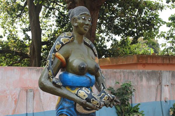 Painted cement statue of woman holding pythons, Temple of Pythons, Ouidah
