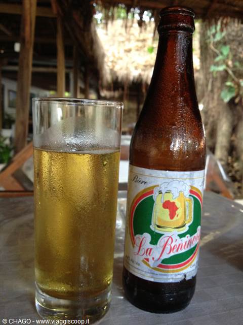 La Beninoise beer bottle and full glass on outdoor table