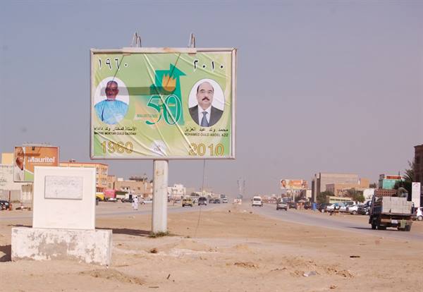 Road billboard celebrating 50 years of independence, sandy street, Mauritania