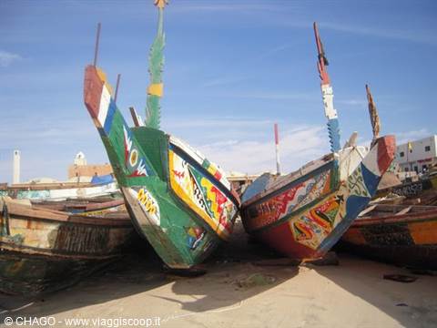 Colorful painted fishing pirogues resting on the sand under blue sky
