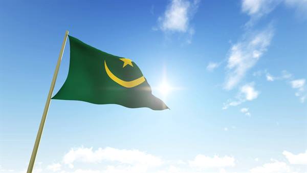 Green flag with yellow crescent and star waving in the wind, sun and clouds