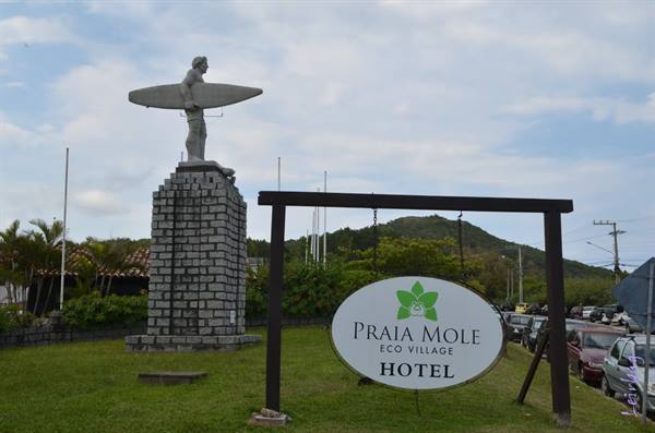 Surfer statue holding surfboard on stone pillar, Praia Mole hotel sign