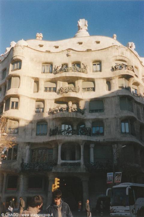 Wavy stone facade of Gaudí's La Pedrera, people crossing the street below