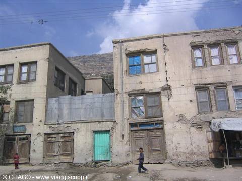 Boy walks past crumbling brick buildings under a cloudy sky