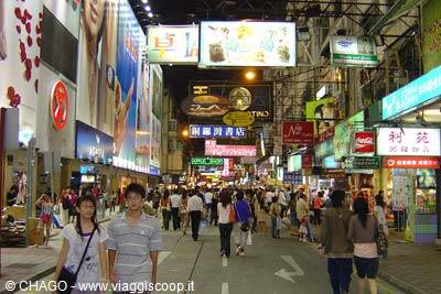 Pedestrians walking along street lit by neon signs