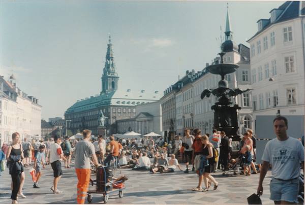 Crowd at Copenhagen square with Caritas fountain and Christiansborg tower