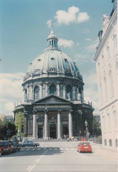 The copper dome of Frederik's Church in Copenhagen between buildings and cars