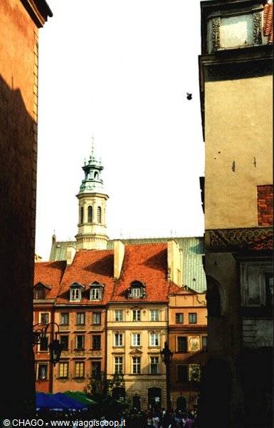 Colorful houses with red roofs and green bell tower in Warsaw Old Town
