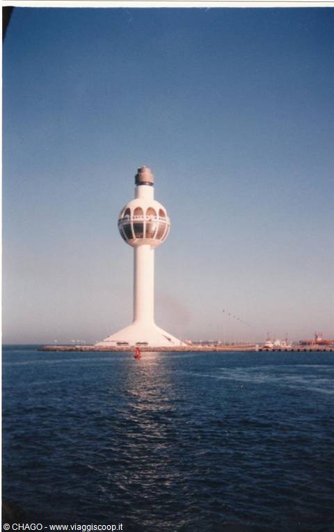 White Jeddah lighthouse on conical base, blue sky, blue sea