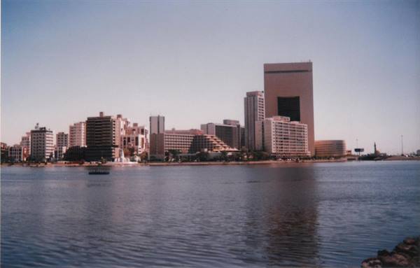 High-rise buildings along Dubai creek, calm waters under blue sky