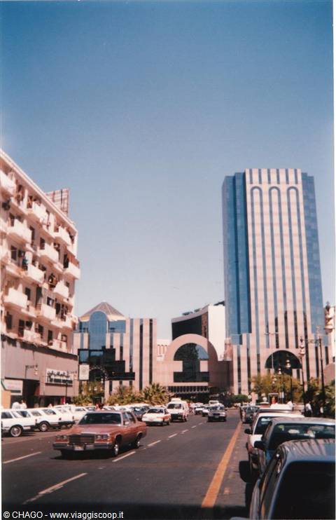 Traffic below glass skyscrapers and apartment balconies under clear blue sky