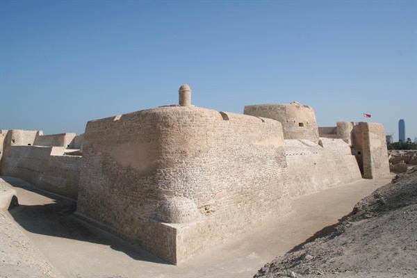 Sunlit stone walls of Qal'at al-Bahrain fort under clear sky