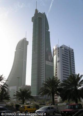 Twin sail-shaped skyscrapers with wind turbines in Manama, palms below