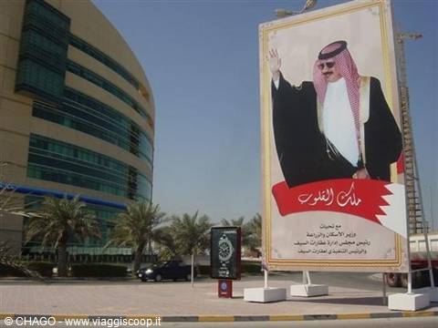 Giant billboard of King Hamad on a Manama street with palm trees