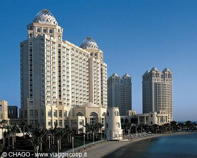 White domed towers along Doha beach under a clear blue sky