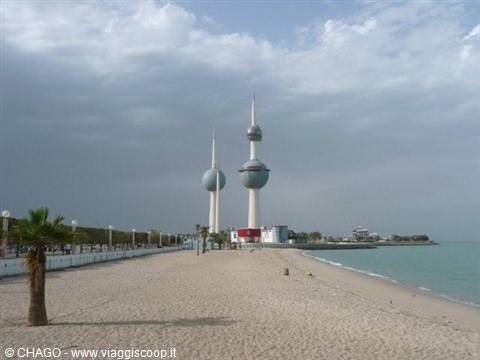 Kuwait Towers above sandy beach, palm tree, cloudy sky