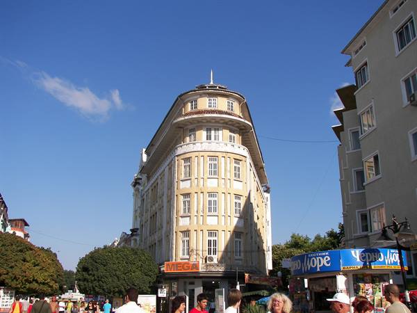 Tourists walk past a yellow Art Nouveau building in Sunny Beach