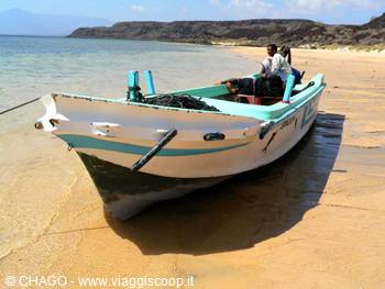 Fishing boat beached on the sand, man at the helm, arid coast