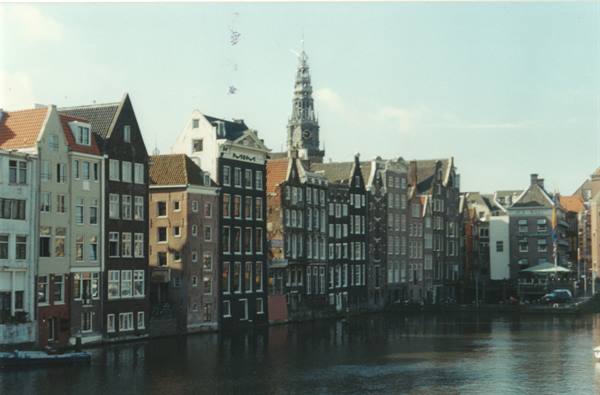 Amsterdam canal houses with the Oude Kerk tower reflected in the water