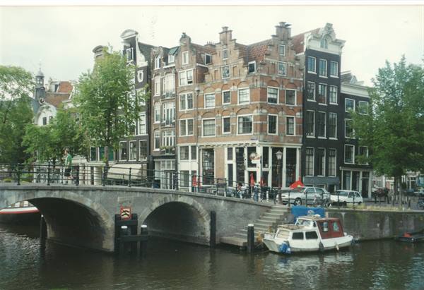 Boat moored under a brick bridge among canal houses in Amsterdam
