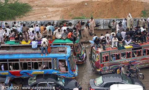 Crowded decorated buses packed with passengers riding on the roof, busy street