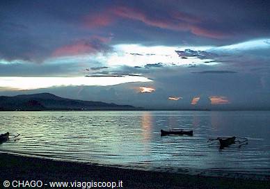 Wooden boats float on calm water beneath pink clouds