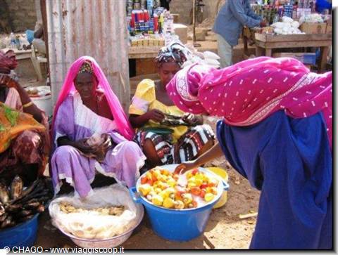 Women in colorful veils sell tomatoes and fish at open-air market