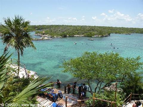 Visitors on the wooden pier at Xel-Há turquoise lagoon among palm trees
