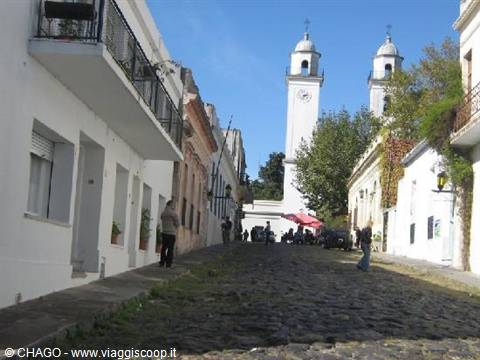 Cobblestone street climbing toward the white church in Colonia del Sacramento