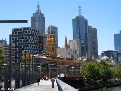 People walk along the river in front of Flinders Street Station, Melbourne