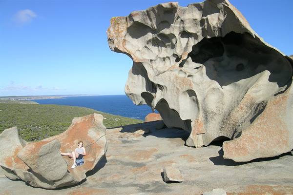 Tourist sitting under the Remarkable Rocks, Kangaroo Island, wind-carved granite