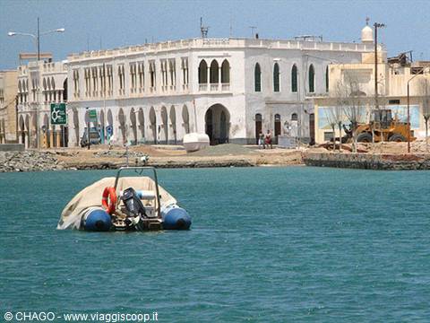 Covered inflatable boat in harbor before white arched colonial building