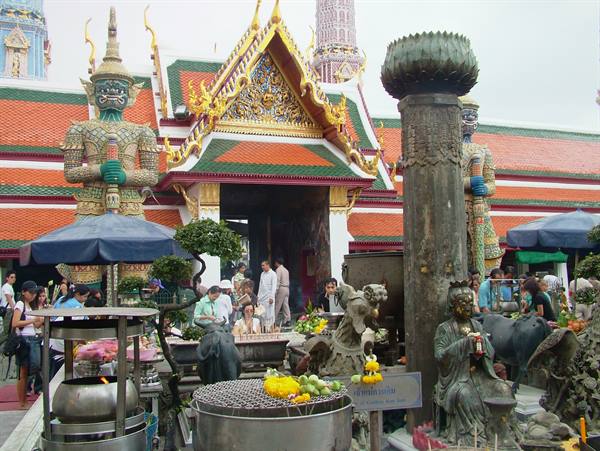 Yak guardian statues at Wat Arun entrance, visitors and flower offerings