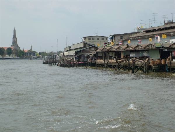 Stilt houses along the Chao Phraya river, Wat Arun temple in the background