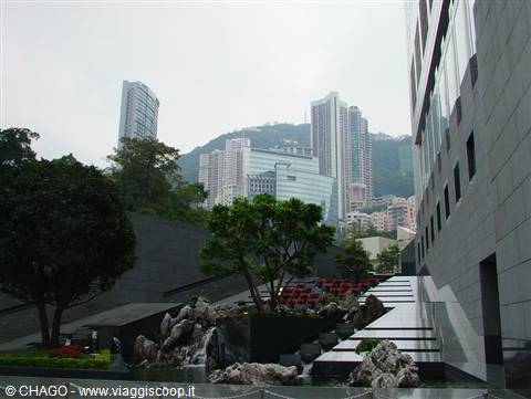 Skyscrapers above the hillside, rocky waterfall garden and stone steps in Hong Kong