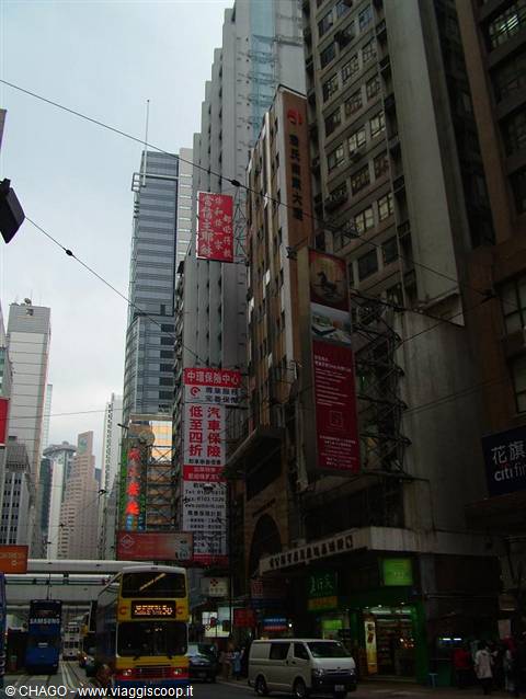 Double-decker bus and tram among skyscrapers with Chinese signs in Hong Kong