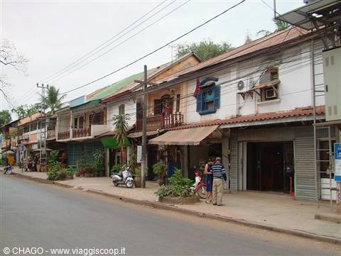 Tourist on street in front of old colonial shophouses with tiled roofs and scooters