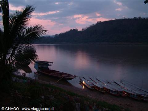Wooden longboats moored on the Mekong under a dusky pink sky