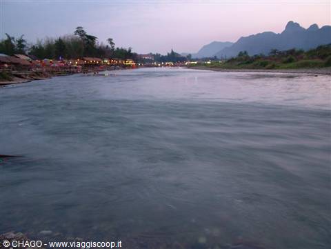 Nam Song river in Vang Vieng, lit riverside restaurants and mountains at dusk