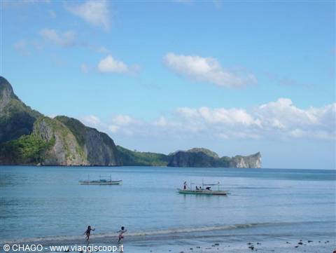 Children playing on the beach, bangka boats in El Nido bay