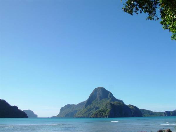 Turquoise sea and green limestone karst mountains under clear blue sky