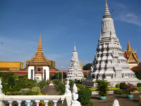 White stupas and golden roof of Phnom Penh Royal Palace under blue sky
