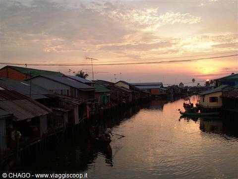 Stilt houses along the canal, fishing boat, pink sky at Kampong Chhnang
